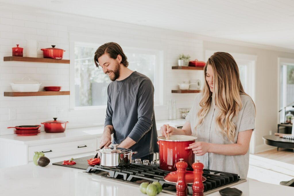 A woman and a man cooking together in front of a stove.